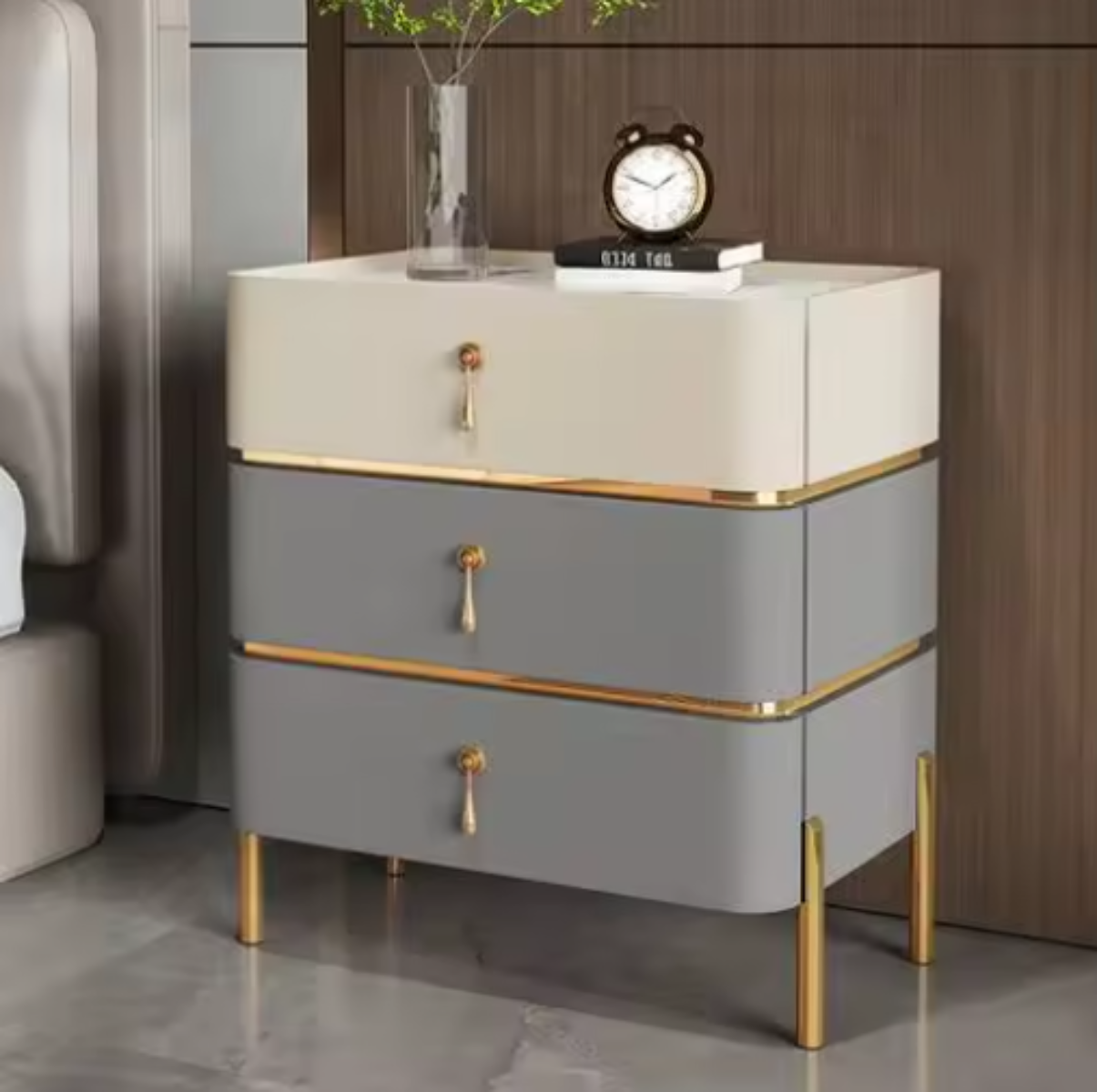 Slate top luxury two-tone beige and slate three-drawer nightstand with white slate top, gold trim, drop-pull handles and slim tapered gold legs styled beside a bed against a walnut wall — LivDecor