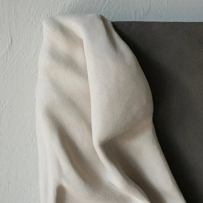 Close-up of the top drape section of the 3D cream fabric resin wall sculpture showing soft fold detail and natural light shadows against the charcoal panel and textured white wall — LivDecor