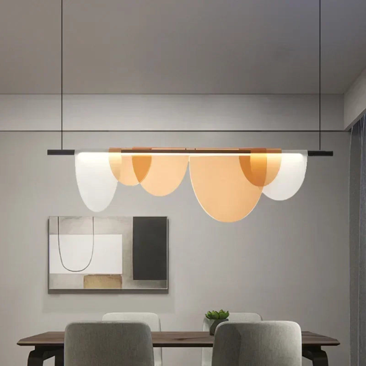 Amber acrylic petal pendant light with five petals illuminated above a dark wood dining table with grey upholstered chairs in a minimal grey dining room — LivDecor