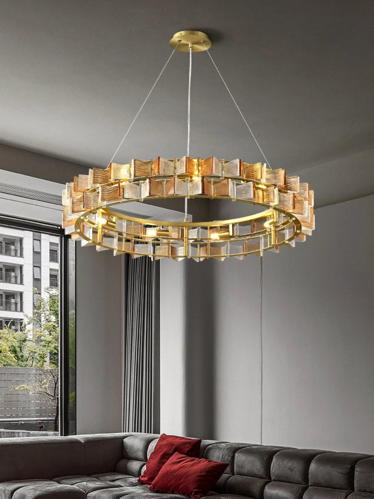 Amber and clear ribbed glass iron round chandelier with gold double-ring frame hanging in a contemporary living room with floor-to-ceiling windows and city view — LivDecor