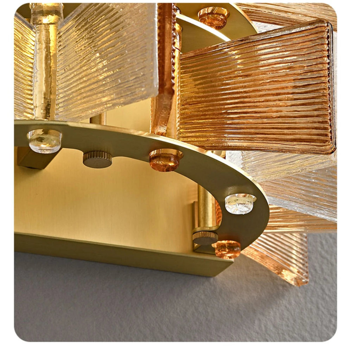 Close-up detail of amber and clear ribbed glass panels and brushed gold wall mount bracket of the glass iron wall sconce showing build quality and hardware finish — LivDecor
