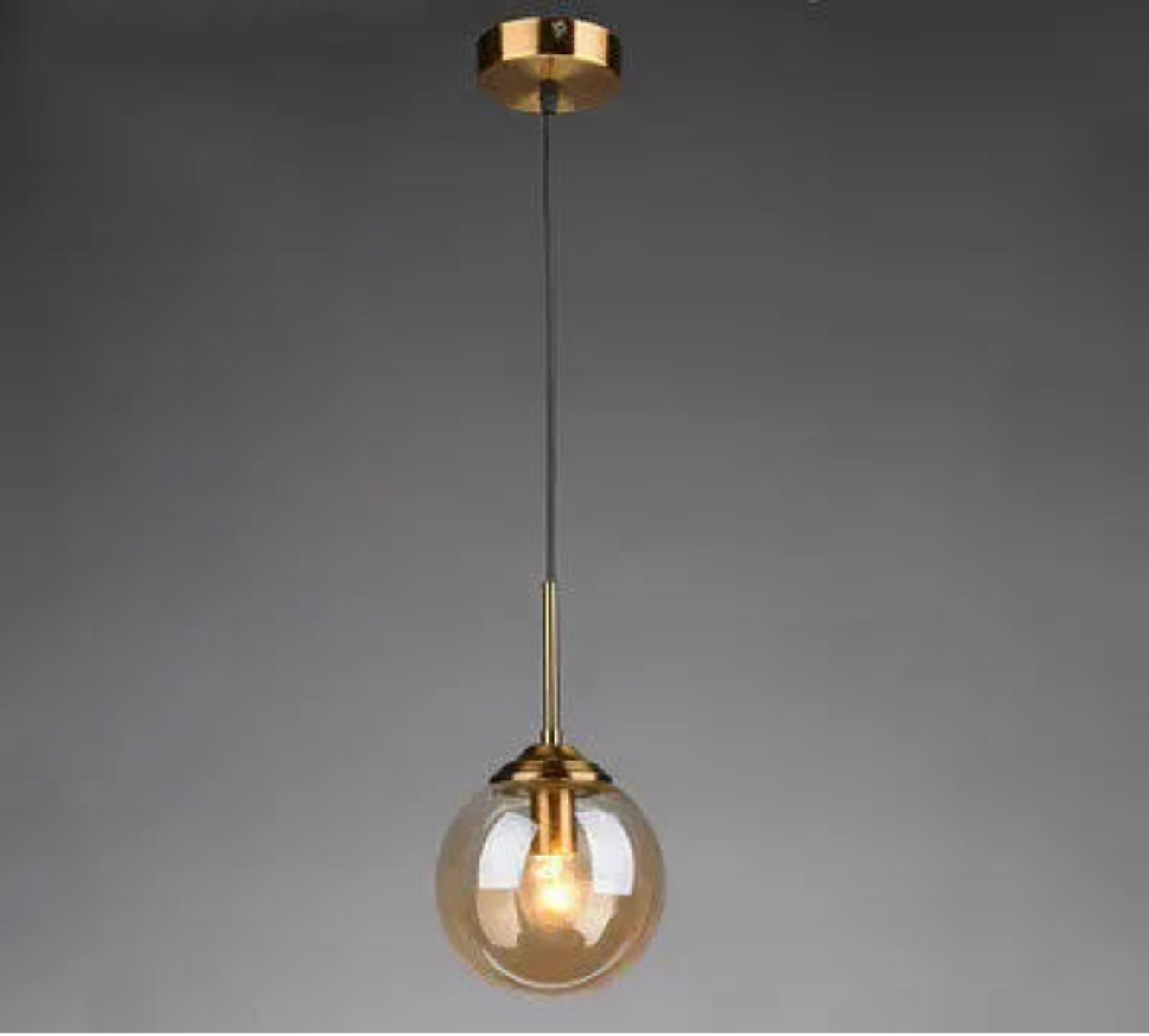 Single amber glass globe pendant light on gold cord and ceiling mount displayed against a neutral grey background — LivDecor