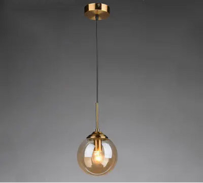 Single amber glass globe pendant light on gold cord and ceiling mount displayed against a neutral grey background — LivDecor