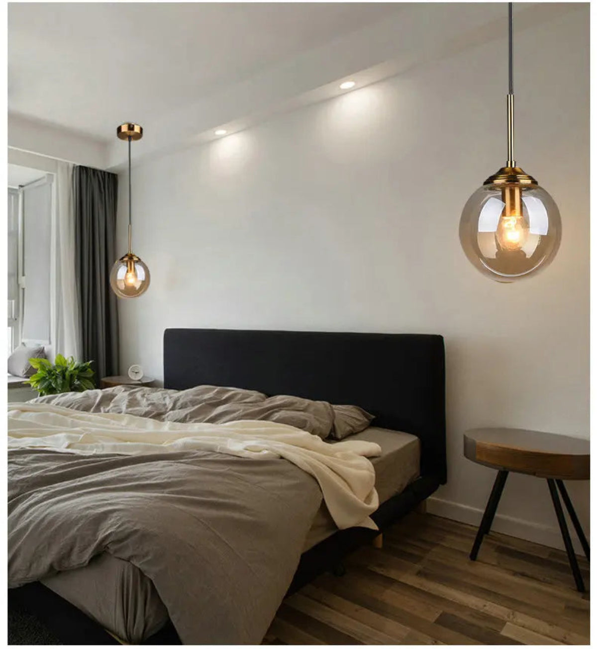 Two amber glass globe pendant lights used as bedside pendants flanking a dark upholstered bed in a modern minimalist bedroom — LivDecor
