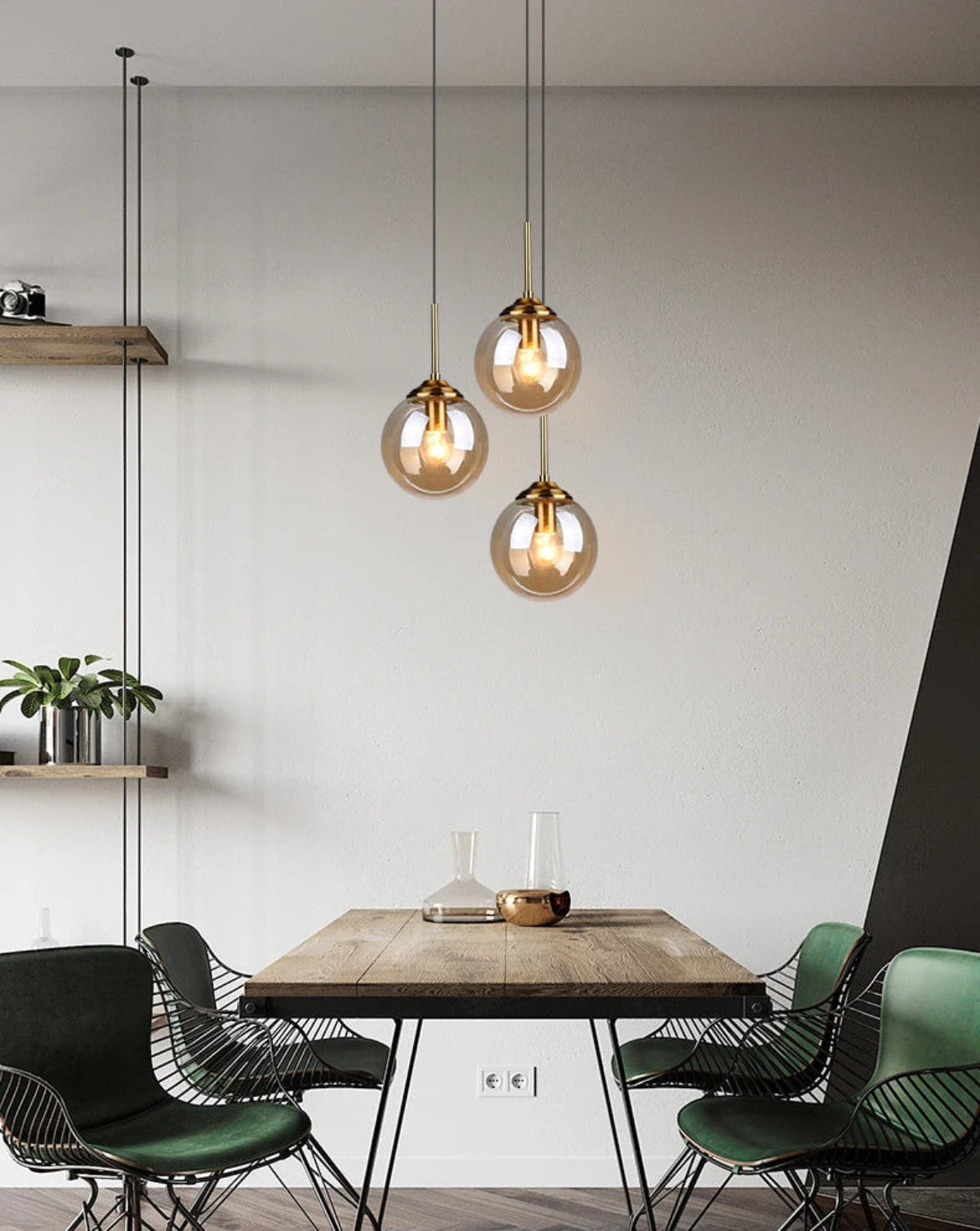 Three amber glass globe pendant lights hanging at staggered heights above an industrial wood dining table with green wire chairs in a modern minimalist dining room — LivDecor
