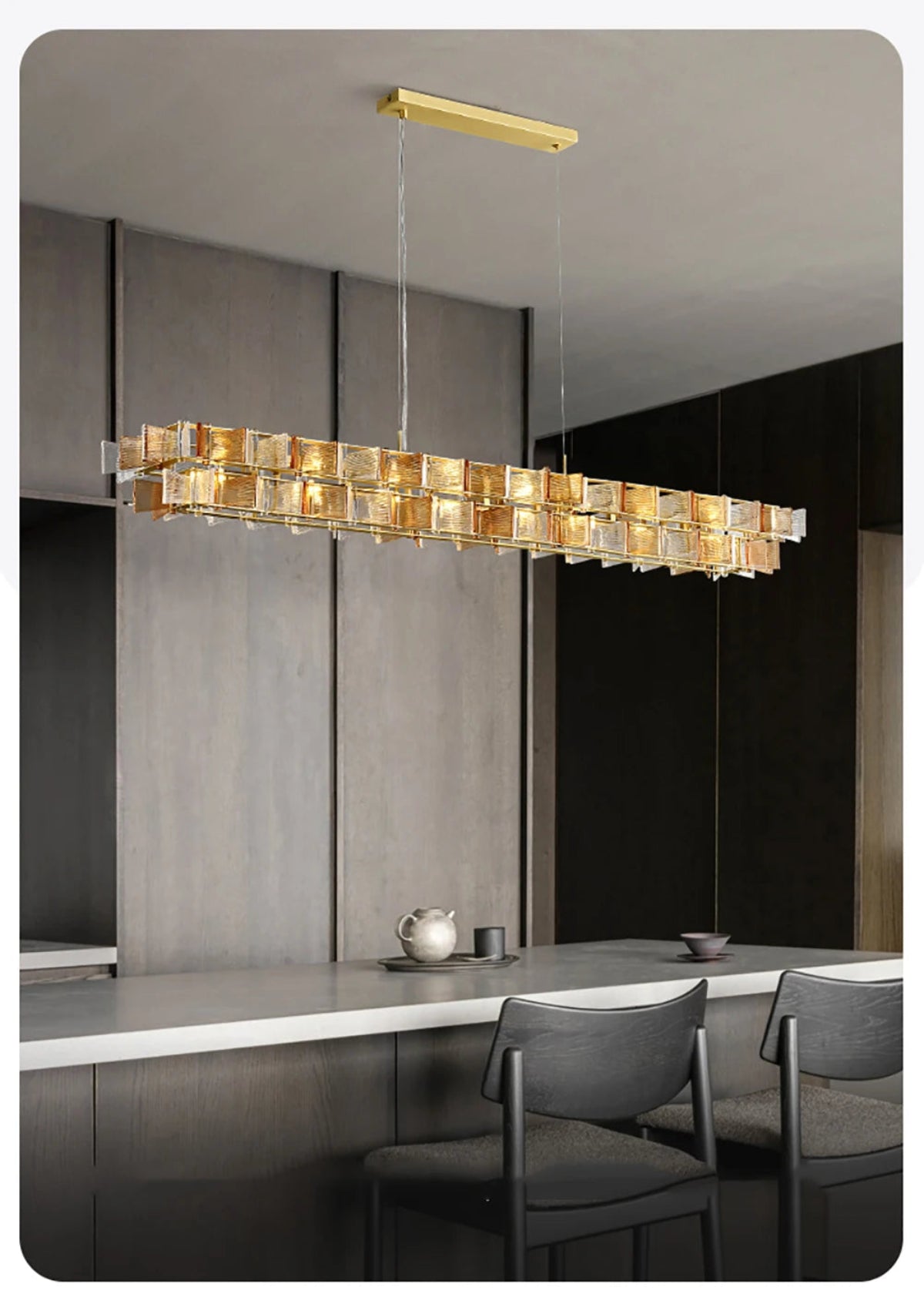 Amber ribbed glass iron linear chandelier with gold rectangular ceiling mount hanging above a modern kitchen island with dining chairs and minimalist tableware — LivDecor