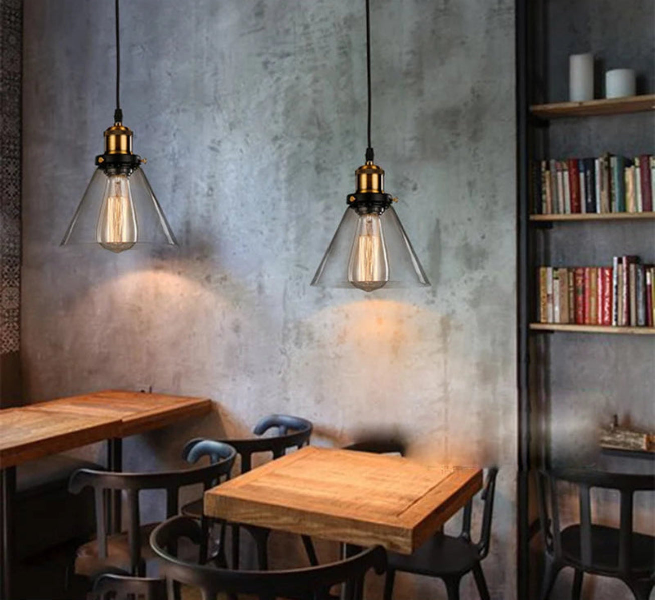 Two clear glass cone pendant lights with antique brass sockets and Edison filament bulbs hanging above rustic wooden café tables against a concrete wall with industrial shelving — LivDecor
