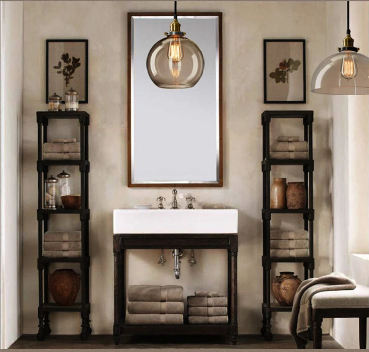 Two clear glass globe pendant lights with antique brass sockets and Edison filament bulbs above an industrial style bathroom vanity with open shelving and botanical wall art — LivDecor
