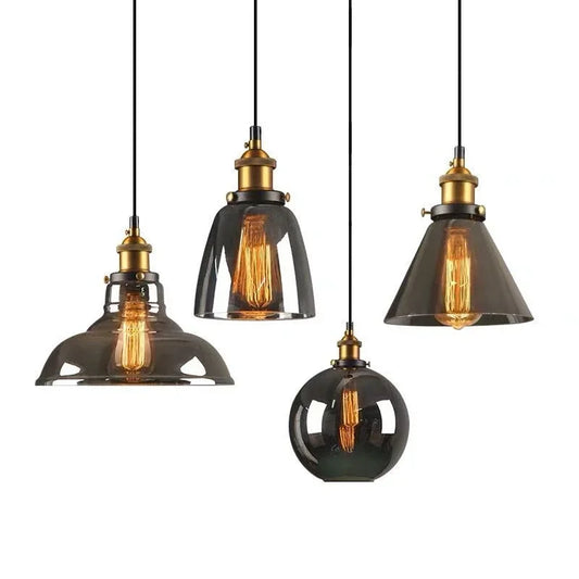 Four smoky gray glass pendant light styles with antique brass sockets and Edison filament bulbs on black cords against a white background — barn, bell, cone, and globe — LivDecor