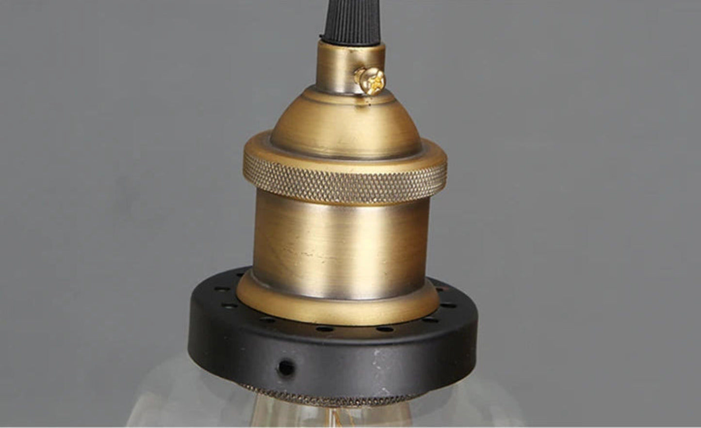 Close-up detail of antique brass knurled socket and matte black ring hardware on a pendant light — LivDecor
