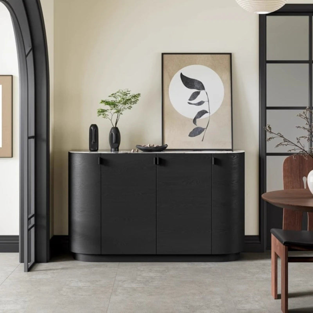 Aura Glass Wabi-Sabi display cabinet in black with marble top shown straight-on with sculptural vases and botanical art in a warm neutral room with arched doorway — LivDecor
