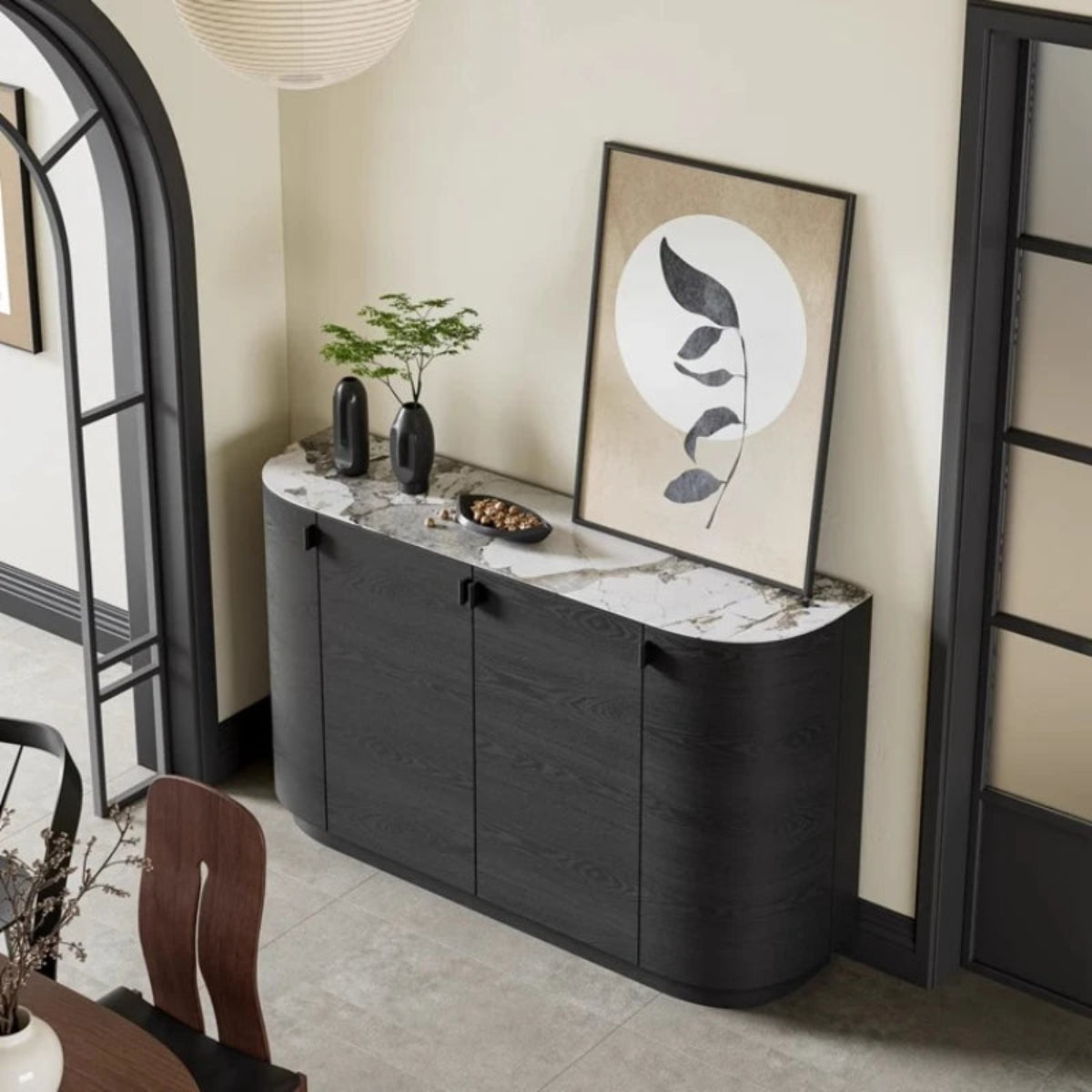 Aura Glass Wabi-Sabi display cabinet in black with marble top styled with sculptural vases and botanical art viewed from an elevated angle in a warm neutral room with arched doorway — LivDecor
