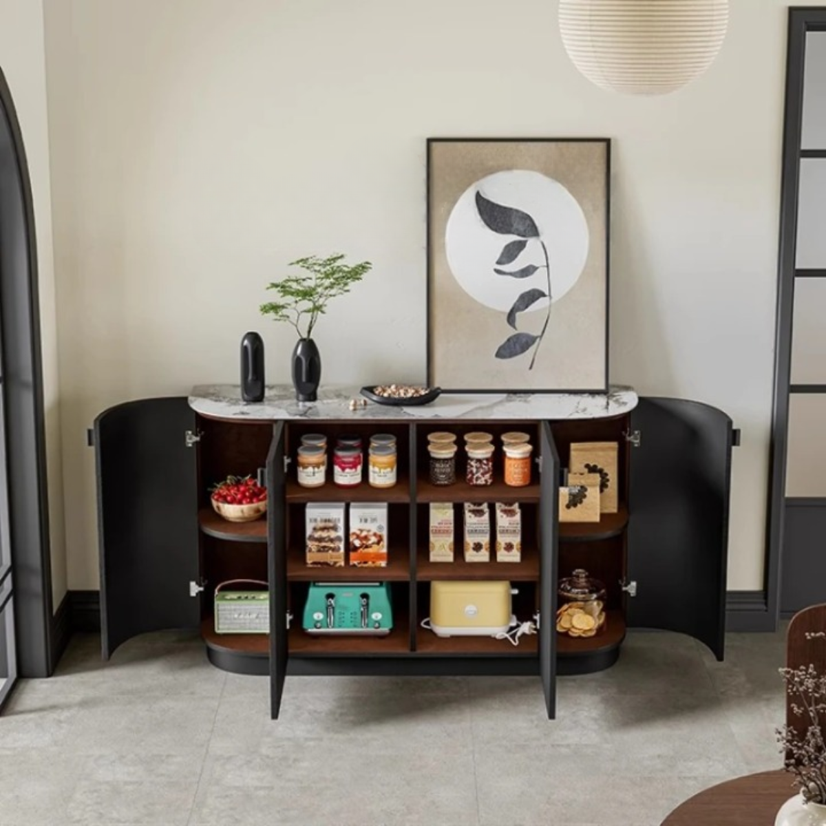 Aura Glass Wabi-Sabi display cabinet in matte black with white marble top and four arched doors open revealing walnut interior shelving styled with pantry goods and small appliances against a warm cream wall with botanical art print — LivDecor
