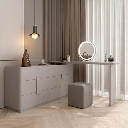 Aura Suite luxury vanity dresser set in greige with 6-drawer chest, integrated vanity desk, round LED mirror, and cube stool in a low wide-angle view with natural light through sheer curtains — LivDecor
