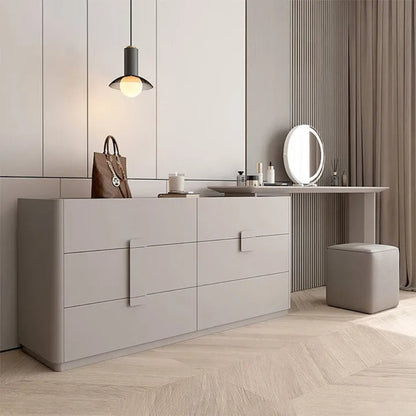 Aura Suite luxury vanity dresser set in light grey with 6-drawer chest, integrated vanity desk extension, round LED mirror, and upholstered cube stool in a minimalist bedroom with herringbone floor — LivDecor
