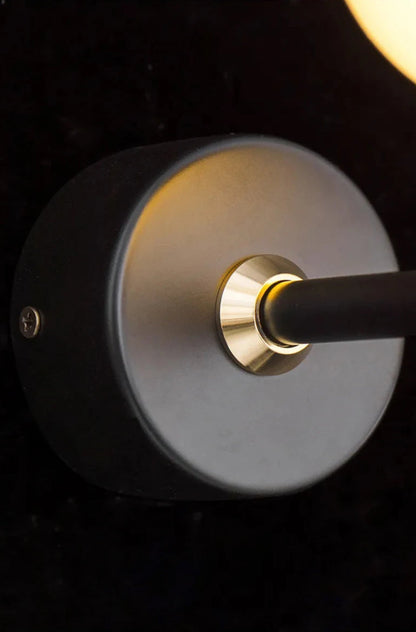 Avis Modern Origami Bird LED wall sconce macro close-up of matte black round wall plate and gold pivot collar where arm meets base with warm bird glow in background — LivDecor
