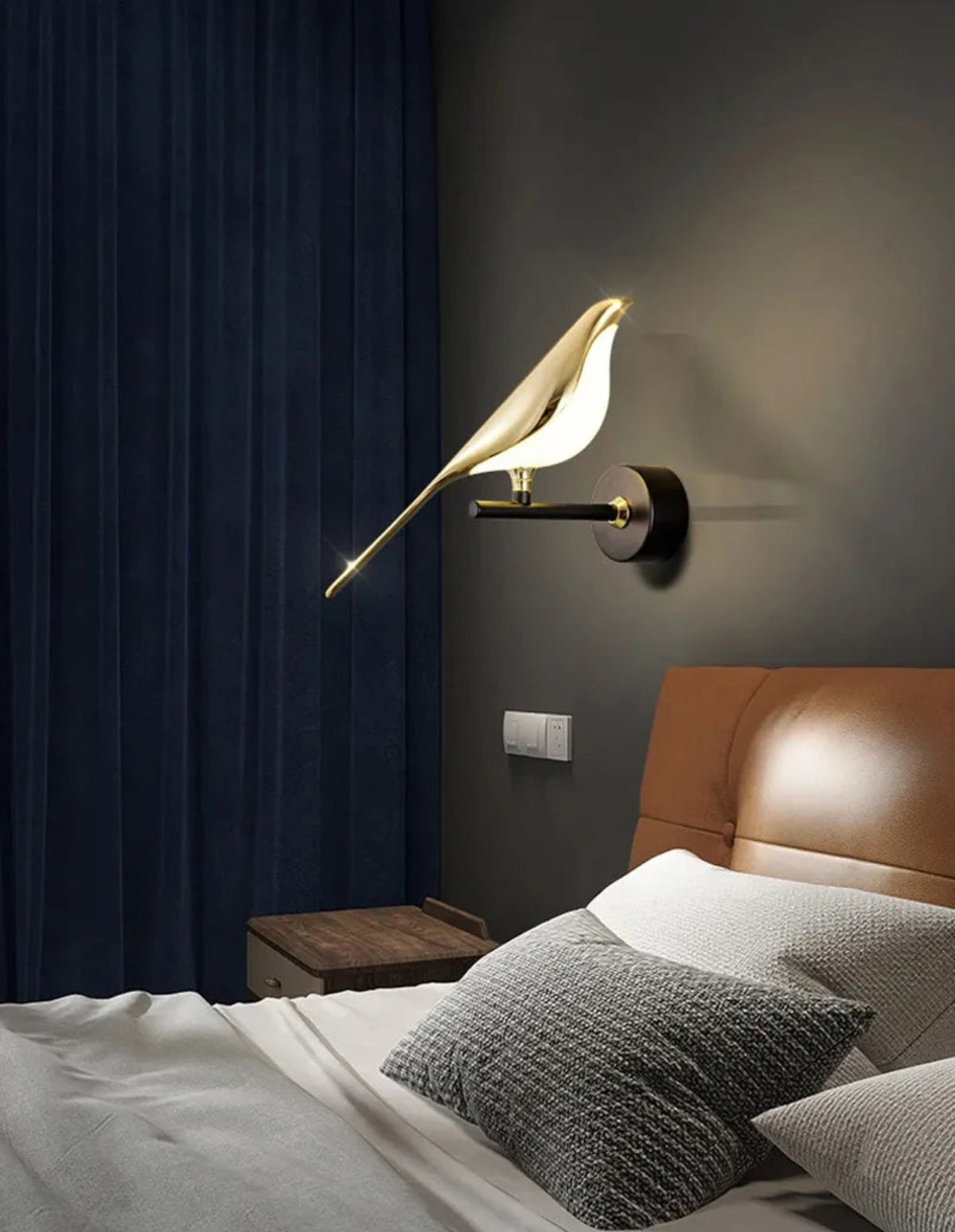 Avis Modern Origami Bird LED wall sconce in gold and matte black single-bird configuration illuminated on a dark charcoal wall with navy velvet drapes, cognac leather headboard, and grey linen bedding — LivDecor
