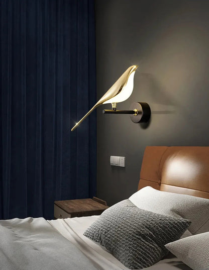 Avis Modern Origami Bird LED wall sconce in gold and matte black single-bird configuration illuminated on a dark charcoal wall with navy velvet drapes, cognac leather headboard, and grey linen bedding — LivDecor
