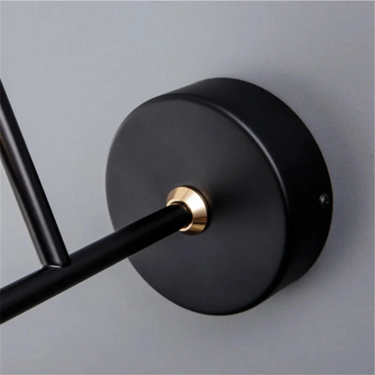 Avis Modern Origami Bird LED wall sconce macro close-up of matte black round wall plate with polished gold collar where the arm exits against a soft grey wall — LivDecor
