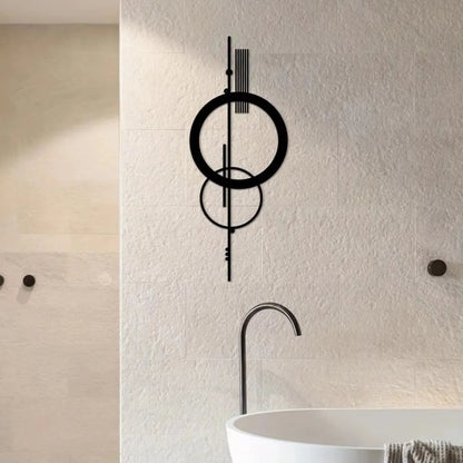 Black metal geometric abstract wall art with double circle and vertical line design mounted on a travertine tile wall in a luxury spa bathroom with a freestanding tub and matte black fixtures — LivDecor