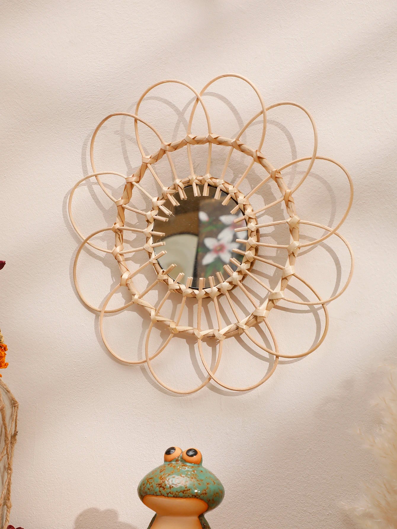 Round boho rattan sunflower wall mirror with woven natural cane petal frame displayed on a cream wall — LivDecor