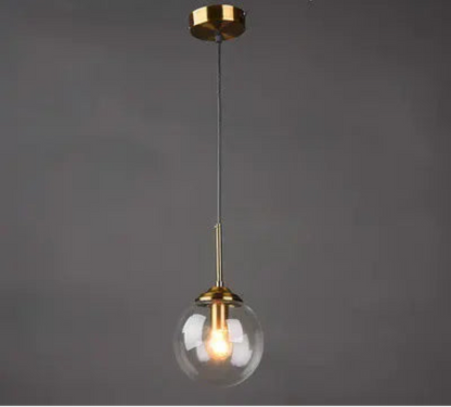Single clear glass globe pendant light on gold cord with round ceiling canopy against a dark grey background — LivDecor
