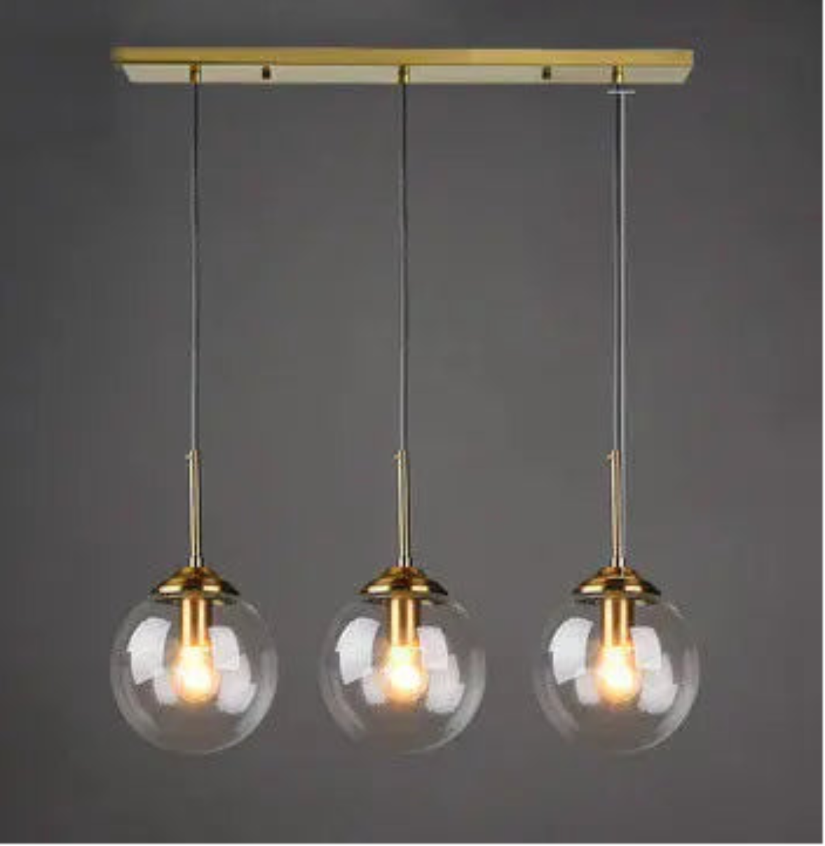 Three clear glass globe pendant lights on gold cord and linear ceiling mount displayed against a neutral grey background — LivDecor