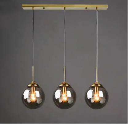 Five clear glass globe pendant lights on staggered gold cords and round ceiling mount in a spiral cluster configuration — LivDecor