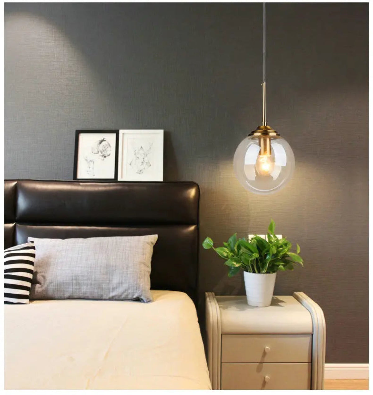 Single clear glass globe pendant light with gold hardware used as a bedside pendant beside a leather headboard against a dark grey wall in a modern bedroom — LivDecor
