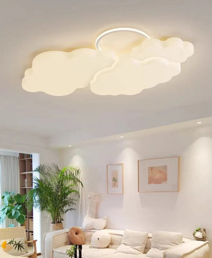 Cumulus Luxe cream sculptural cloud LED ceiling light with halo ring glowing soft white in a warm cream living room with tropical plant, framed art, and plush sofa — LivDecor
