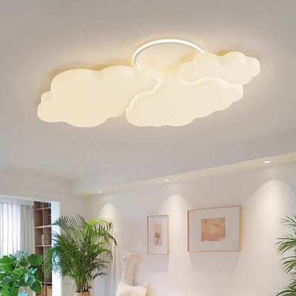 Cumulus Luxe cream sculptural cloud LED ceiling light with halo ring glowing warm white in a bright white living room with tropical plants, framed art, and recessed ceiling lights — LivDecor
