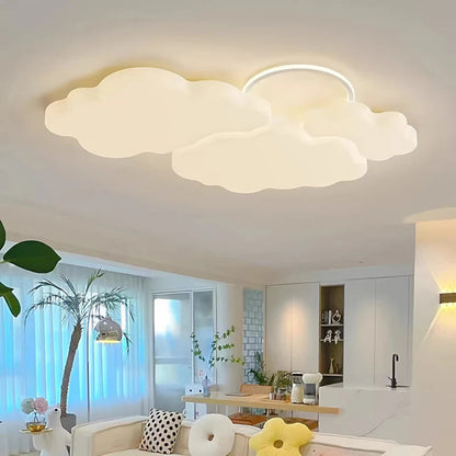 Cumulus Luxe cream sculptural cloud LED ceiling light with halo ring glowing warm white in a bright open-plan living and dining space with palm tree, modern kitchen, and daisy cushions — LivDecor

