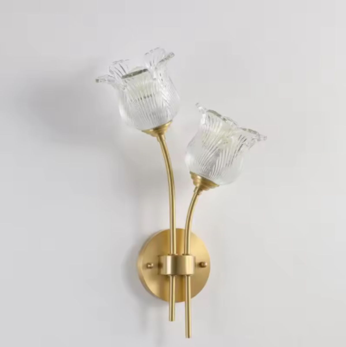 Flora Luxe botanical brass double-head wall sconce with two ruffled floral glass shades angled right on a round backplate against a white wall — LivDecor
