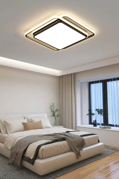 Halo modern tricolor LED flush mount ceiling light in matte black square frame glowing warm white installed in a bright modern bedroom with cove lighting, linen bedding, and floor-to-ceiling curtains — LivDecor
