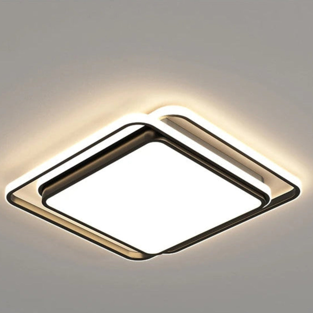 Halo modern tricolor LED flush mount ceiling light in matte black square frame switched on showing warm amber halo glow on a grey ceiling — LivDecor
