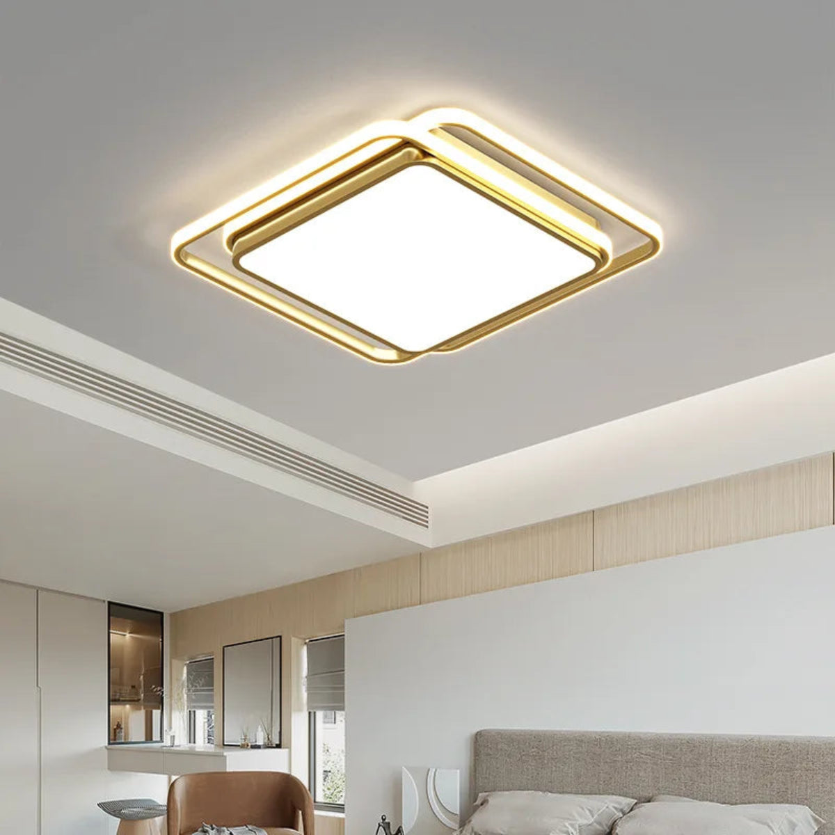 Halo modern tricolor LED flush mount ceiling light in golden square frame glowing warm white in an open-plan bedroom with cove ceiling lighting, leather chair, and neutral wood tones — LivDecor
