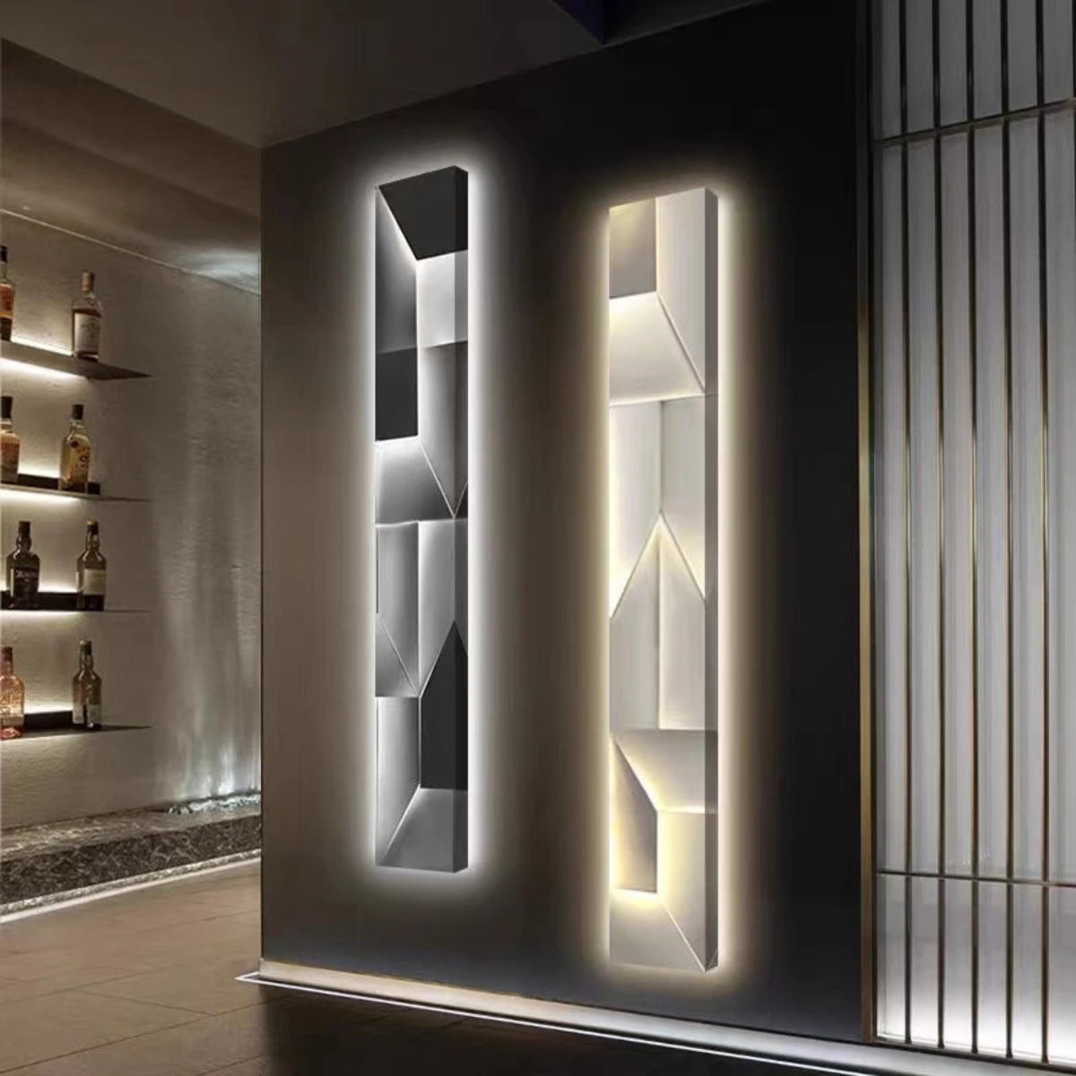 Luminary Canvas backlit crystal art wall sconce in vertical configuration shown in cool and warm LED tones side by side in a moody bar lounge with backlit liquor shelving — LivDecor
