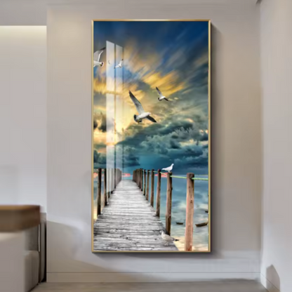Gold-framed illuminated mural of a wooden pier stretching into a blue and gold sunset sky with flying seagulls, mounted in a hallway entryway above a bench — LivDecor

