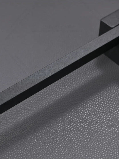Close-up detail of minimalist linear LED wall sconce matte black textured finish and slim profile against a grey background — LivDecor
