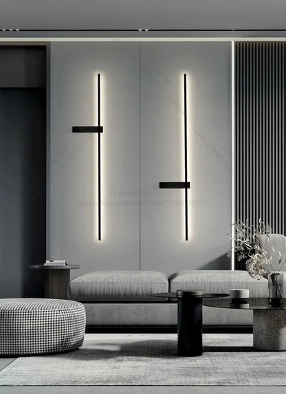 Pair of minimalist linear LED wall sconces in matte black mounted symmetrically above a grey sofa in a modern monochrome living room lifestyle shot — LivDecor
