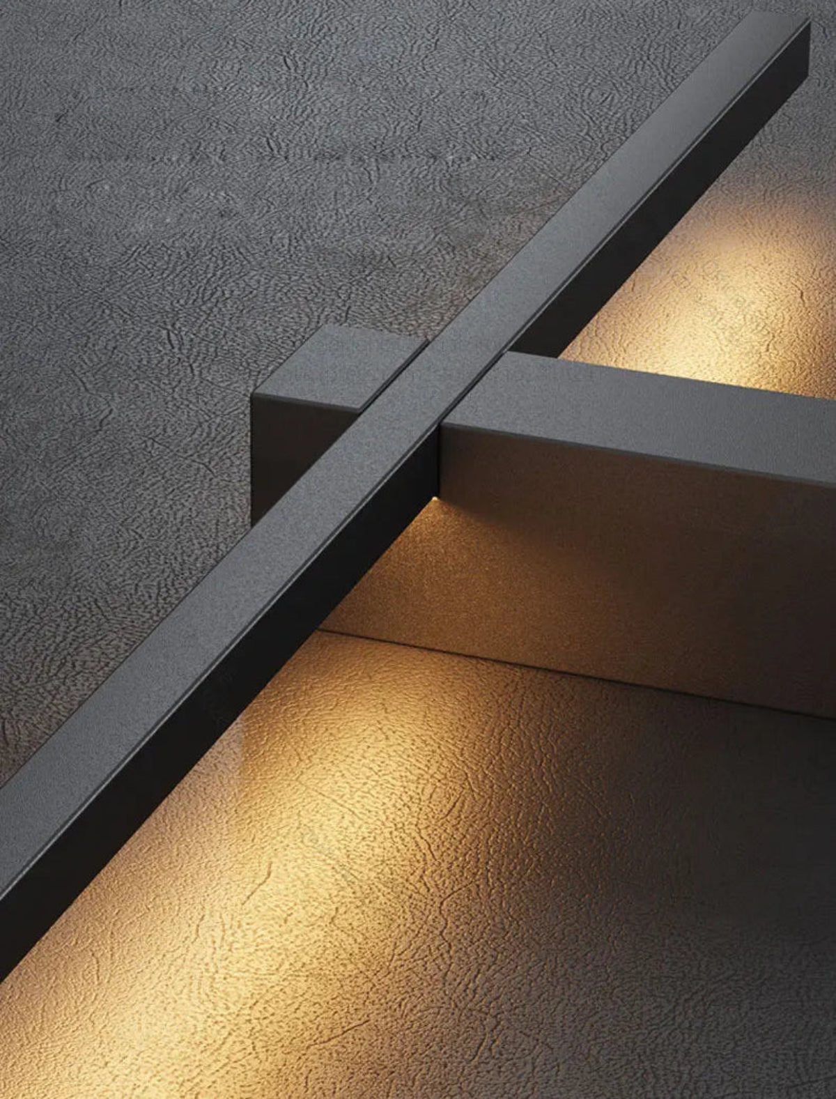 Close-up detail of minimalist linear LED wall sconce in matte black casting warm amber glow against a textured concrete wall — LivDecor
