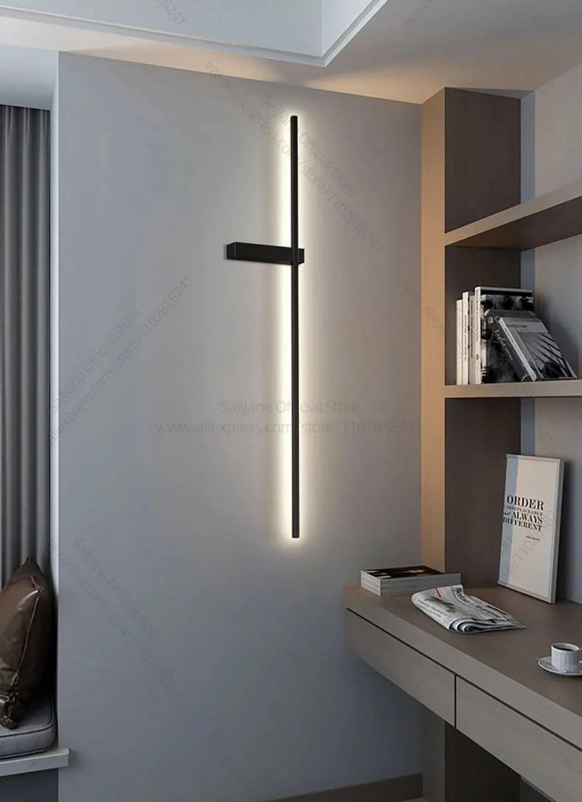 Single minimalist linear LED wall sconce in matte black mounted vertically on a grey concrete wall beside a modern home office desk and shelving unit lifestyle shot — LivDecor
