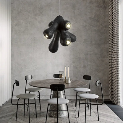 Odense Cocoon sculptural cloud pendant chandelier in black 4-head cluster hanging over a round marble-base dining table with black Afteroom chairs against a concrete wall with herringbone floor — LivDecor
