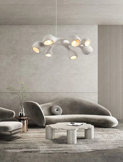 Odense Cocoon sculptural cloud pendant chandelier in white 3-head linear configuration hanging in a Mediterranean arch living room with tropical greenery, round wood coffee table, and bouclé chairs — LivDecor
