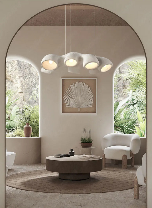 Odense Cocoon sculptural cloud pendant chandelier in white 3-head linear configuration hanging in a Mediterranean arch living room with tropical greenery, round wood coffee table, and bouclé chairs — LivDecor
