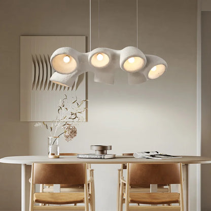 Odense Cocoon sculptural cloud pendant chandelier in white 3-head linear configuration fully lit over a white oval dining table with natural oak wishbone chairs and dried botanicals — LivDecor
