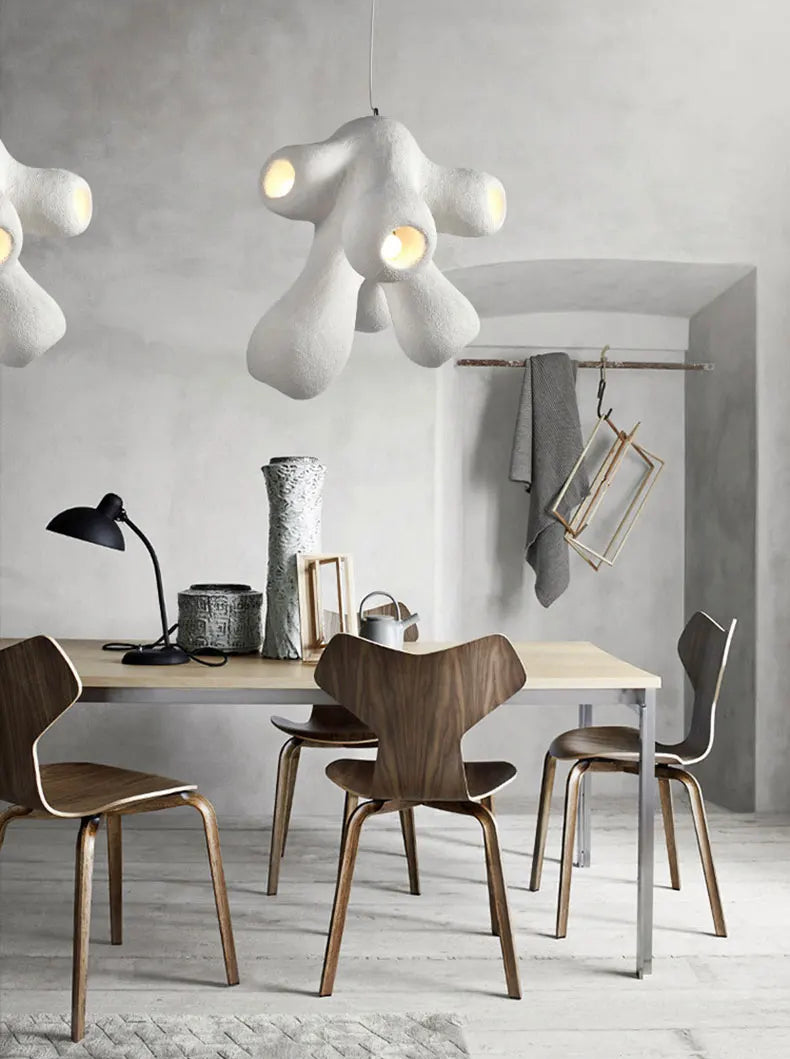 Two Odense Cocoon sculptural cloud pendant chandeliers in white 4-head configuration hung at staggered heights over a wood dining table with walnut Grand Prix chairs in a Scandinavian concrete dining room — LivDecor
