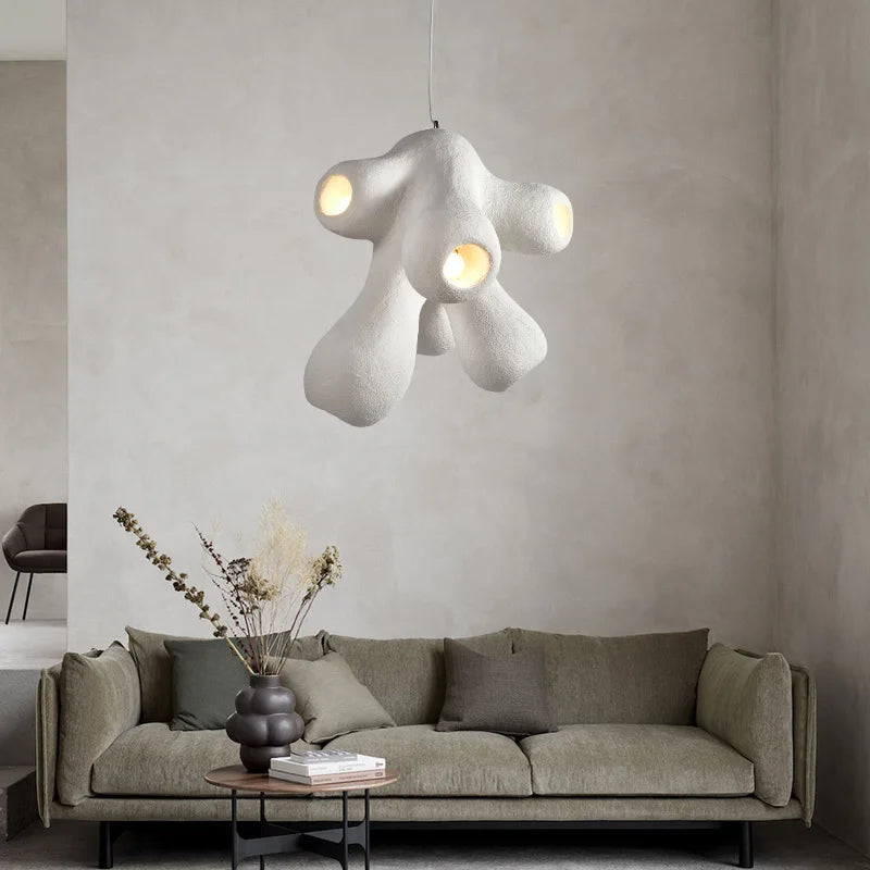 Odense Cocoon sculptural cloud pendant chandelier in white 4-head cluster hanging above a sage green sofa with dried botanicals in a black bubble vase against a warm grey plaster wall — LivDecor
