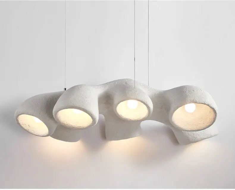 Odense Cocoon sculptural cloud pendant chandelier in white with 4 individual downward-facing cavity pendants hung in a linear row fully lit with warm glow against a neutral white background — LivDecor
