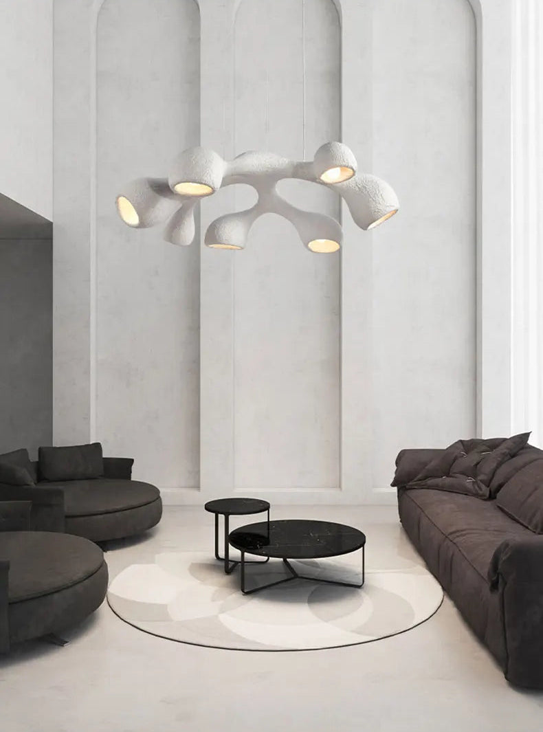 Odense Cocoon sculptural cloud pendant chandelier in white 7-head flat configuration hanging in a grand arched white hall above charcoal modular sofas and black marble nesting coffee tables — LivDecor

